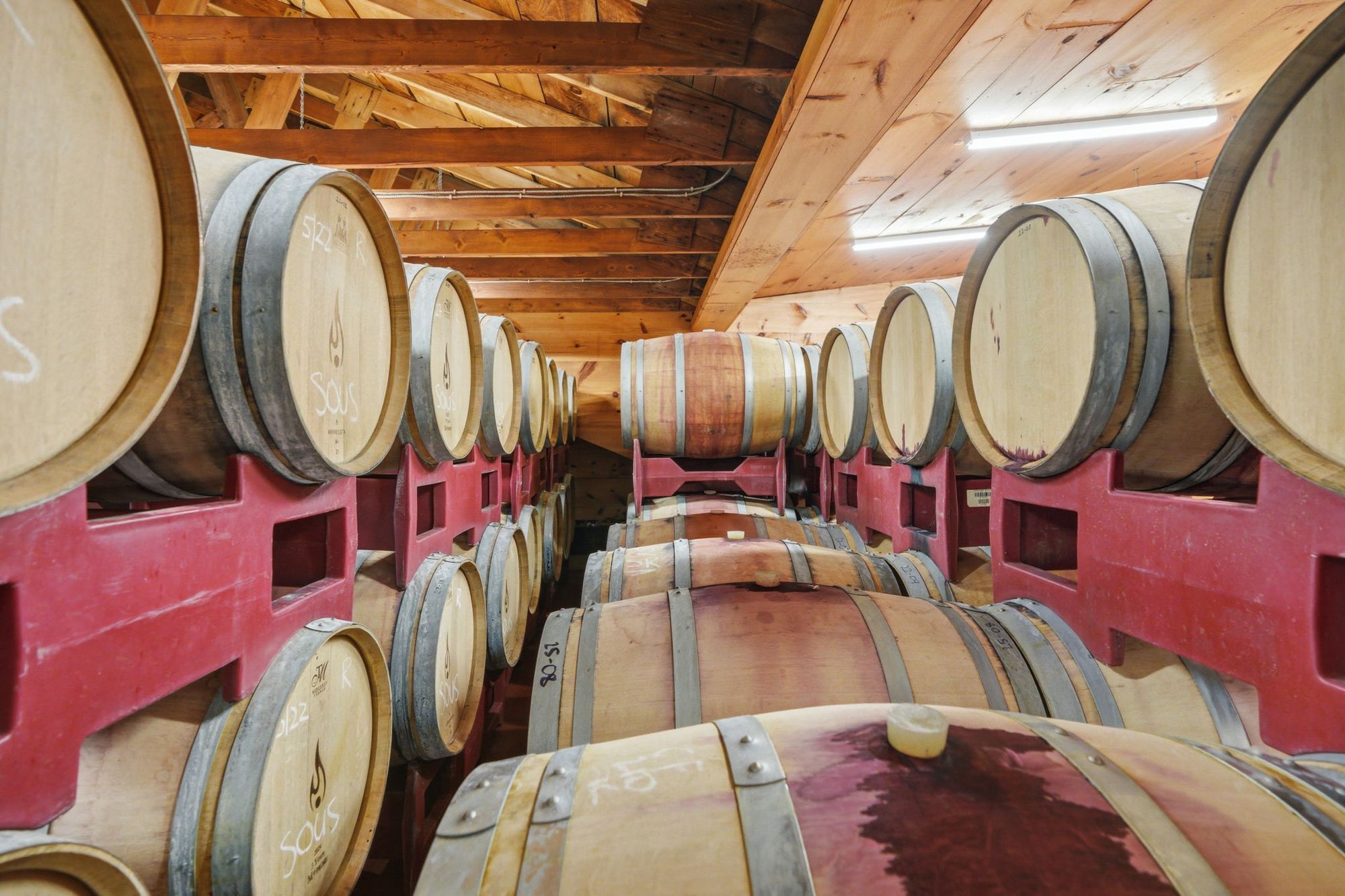 The barrel room, stacked two high under a timber ceiling