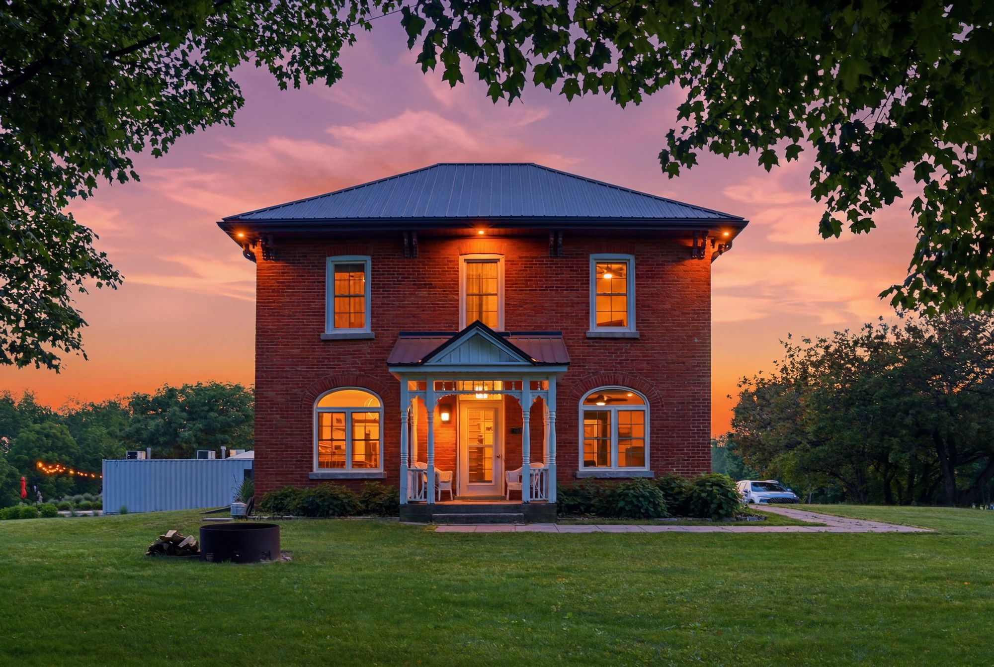 The brick guest house at dusk, its windows lit