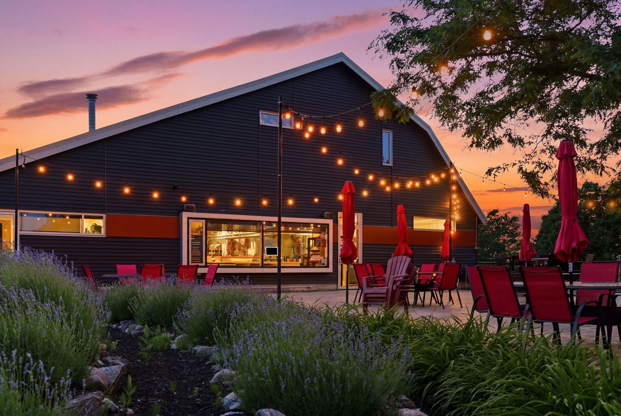 The patio under string lights at dusk, red umbrellas furled and lavender in the beds