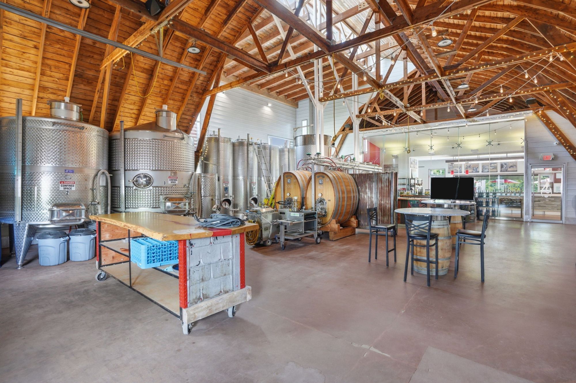 The production hall under timber trusses: tanks, barrels and the tasting bar